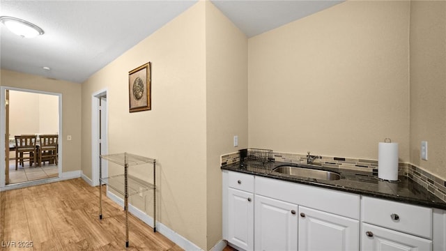 bathroom with decorative backsplash, a sink, baseboards, and wood finished floors