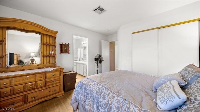 bedroom with light hardwood / wood-style flooring, a closet, and ensuite bathroom