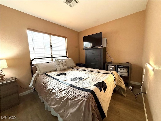 bedroom featuring visible vents, baseboards, and wood finished floors