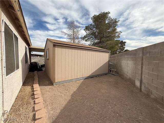 view of home's exterior with a storage shed, a fenced backyard, and an outbuilding