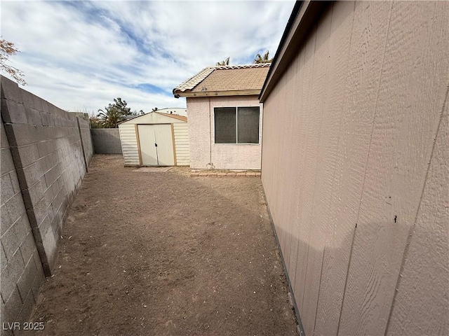 view of yard with a fenced backyard, an outdoor structure, and a storage shed