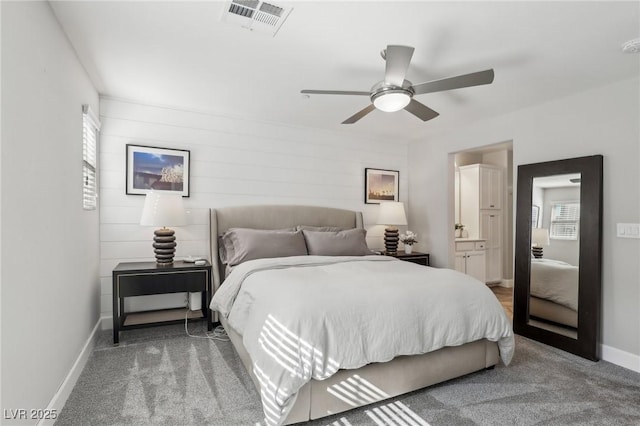 carpeted bedroom with visible vents, a ceiling fan, ensuite bathroom, and baseboards