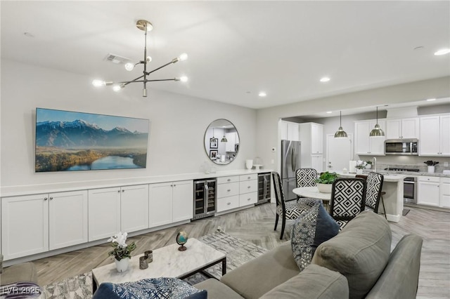 living room featuring recessed lighting, visible vents, a notable chandelier, and beverage cooler