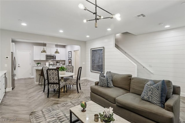 living area with visible vents, recessed lighting, arched walkways, an inviting chandelier, and baseboards