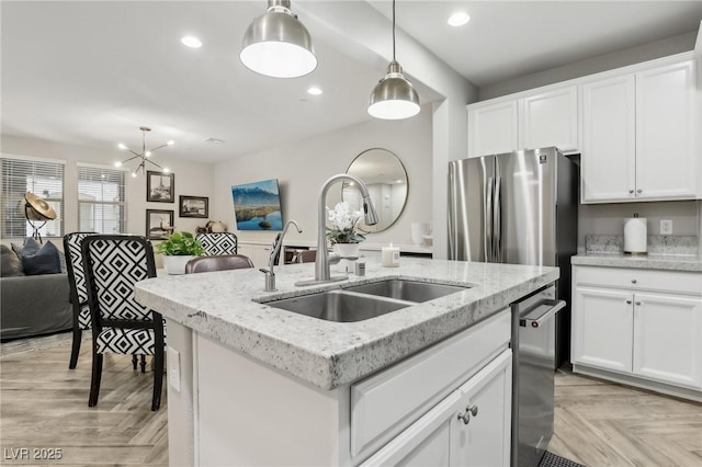 kitchen featuring hanging light fixtures, a center island with sink, stainless steel appliances, and a sink