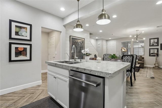 kitchen with hanging light fixtures, a sink, white cabinets, and stainless steel dishwasher