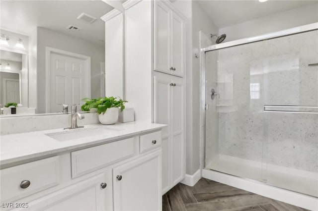 bathroom featuring visible vents, a stall shower, and vanity