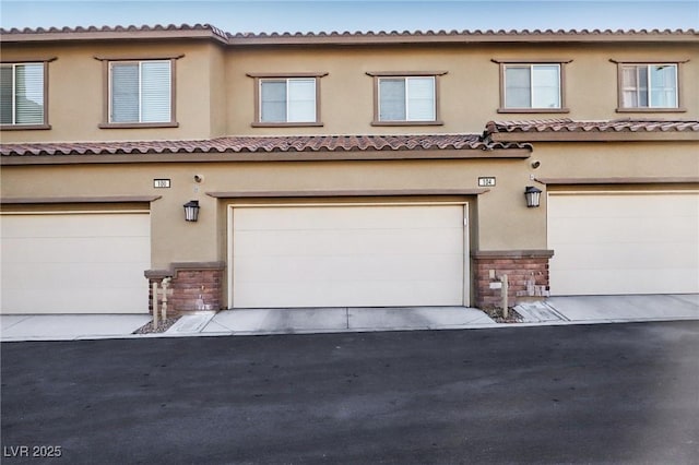 view of property with aphalt driveway, an attached garage, and stucco siding