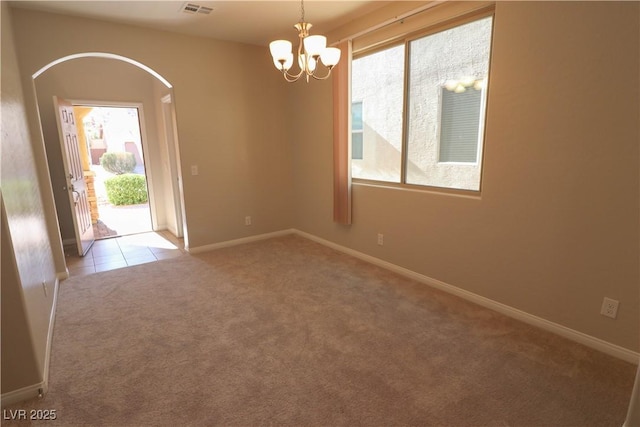 empty room featuring a notable chandelier and light colored carpet