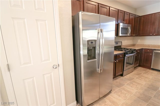 kitchen with stainless steel appliances, light stone countertops, and dark brown cabinets