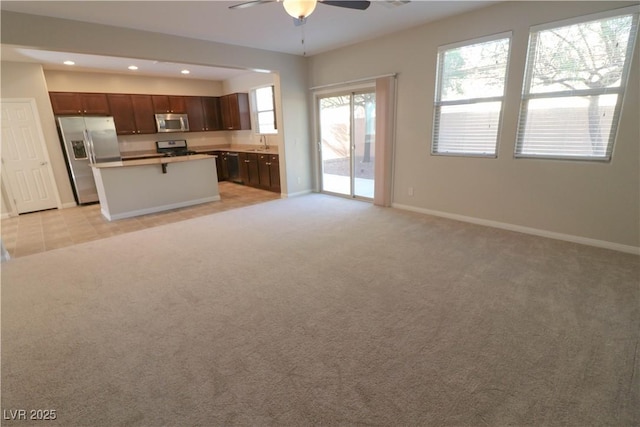 kitchen featuring a kitchen island, appliances with stainless steel finishes, sink, light colored carpet, and ceiling fan