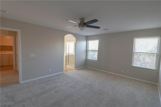 unfurnished room with ceiling fan, washing machine and clothes dryer, and light carpet