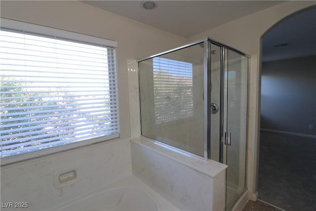 bathroom featuring independent shower and bath and a wealth of natural light