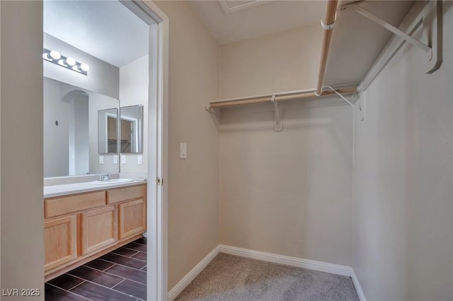 walk in closet featuring sink and dark colored carpet