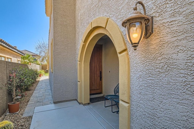 property entrance with fence and stucco siding