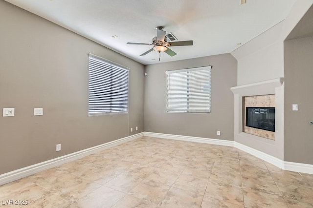 unfurnished living room with visible vents, baseboards, a ceiling fan, and a glass covered fireplace