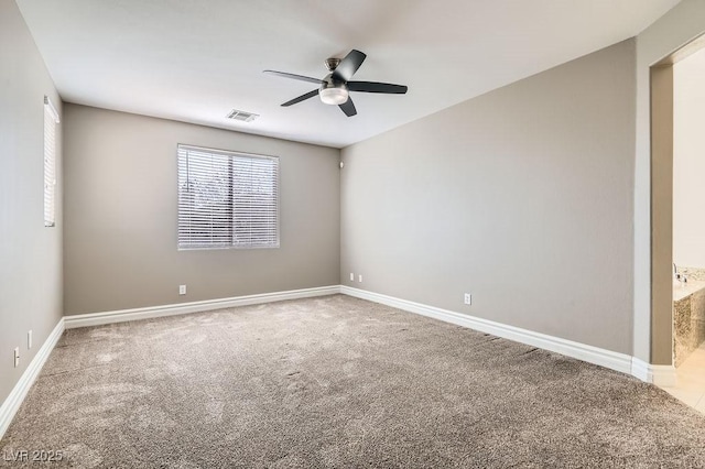 carpeted spare room with ceiling fan, visible vents, and baseboards