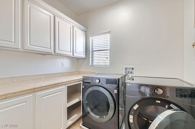 washroom with cabinet space, separate washer and dryer, and light tile patterned flooring