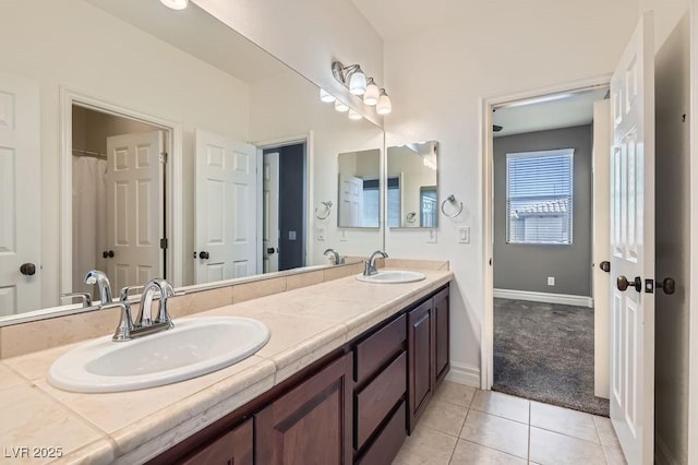 bathroom featuring double vanity, baseboards, a sink, and tile patterned floors