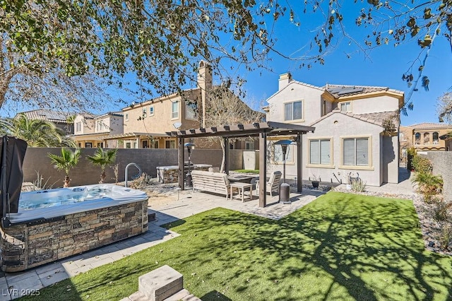 back of house featuring a yard, stucco siding, a hot tub, a pergola, and a fenced backyard