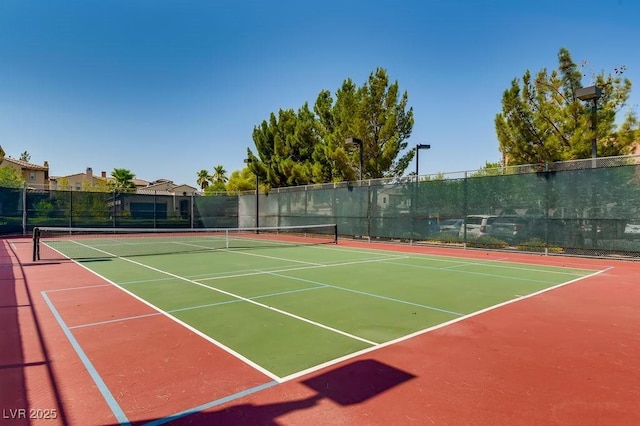 view of tennis court featuring community basketball court and fence