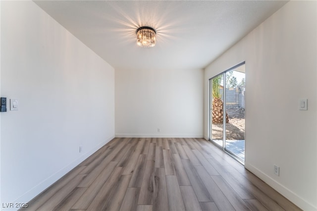 unfurnished room featuring wood-type flooring and an inviting chandelier