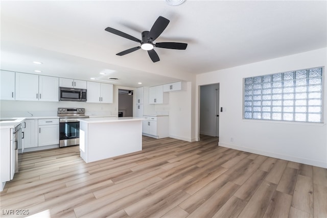 kitchen with a kitchen island, appliances with stainless steel finishes, white cabinets, and light hardwood / wood-style floors