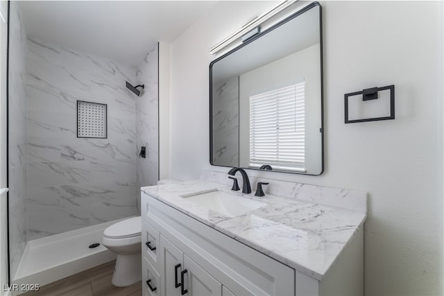 bathroom featuring vanity, toilet, wood-type flooring, and a tile shower