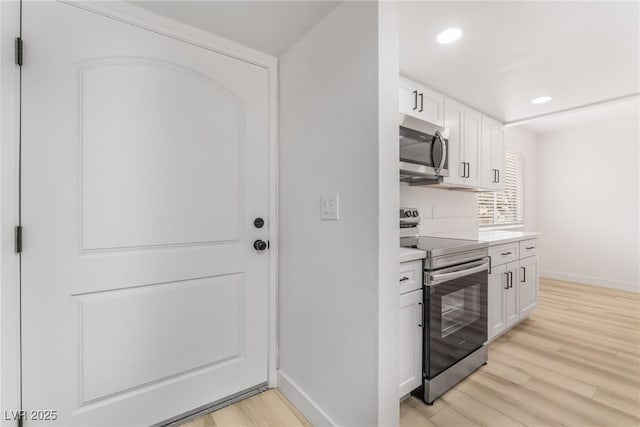 kitchen with white cabinetry, stainless steel appliances, and light hardwood / wood-style floors