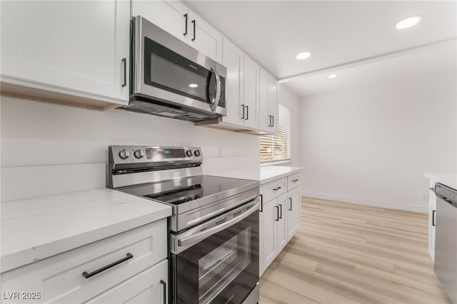 kitchen featuring stainless steel appliances, light wood-type flooring, white cabinets, and light stone counters