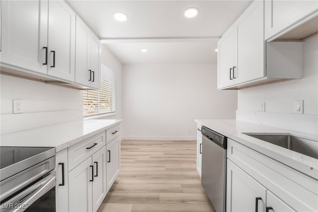 kitchen with white cabinetry, appliances with stainless steel finishes, light stone countertops, and light hardwood / wood-style floors