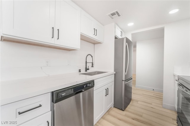 kitchen with white cabinetry, sink, stainless steel appliances, and light wood-type flooring