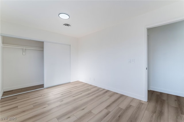 unfurnished bedroom with a closet and light hardwood / wood-style flooring