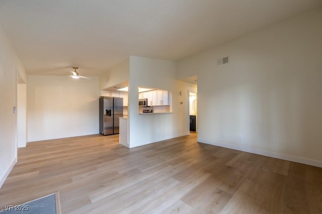 unfurnished living room with ceiling fan, vaulted ceiling, and light wood-type flooring