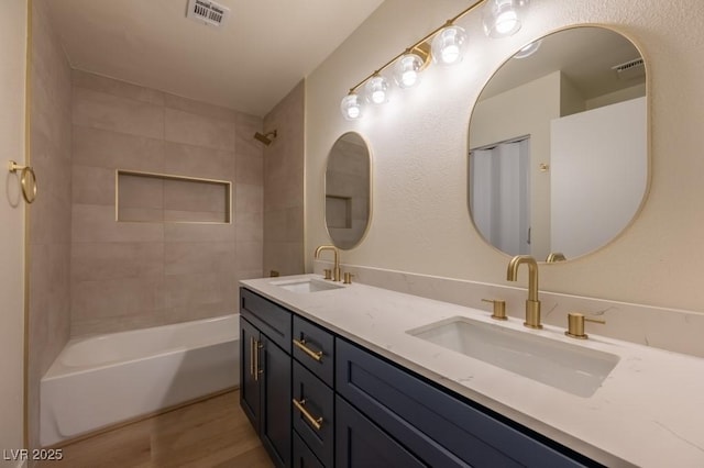 bathroom with vanity, hardwood / wood-style floors, and tiled shower / bath