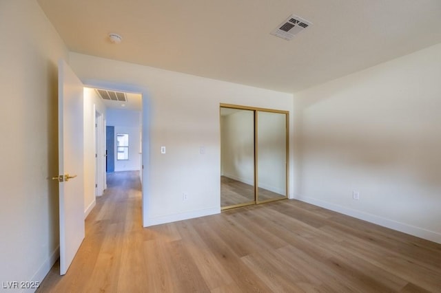 unfurnished bedroom with a closet and light wood-type flooring