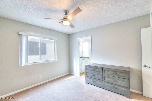 unfurnished bedroom with light carpet, connected bathroom, a textured ceiling, and baseboards