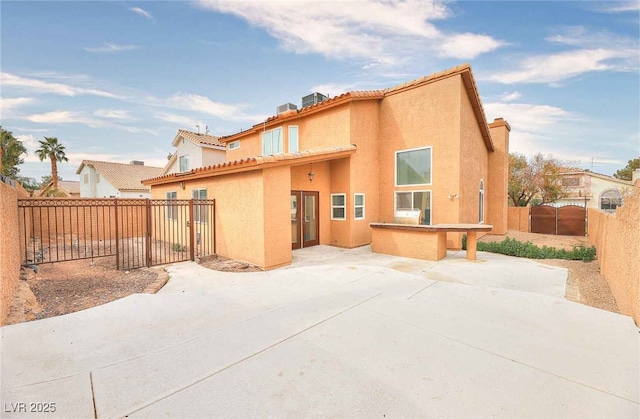 rear view of house with a tiled roof, a patio area, a fenced backyard, and stucco siding