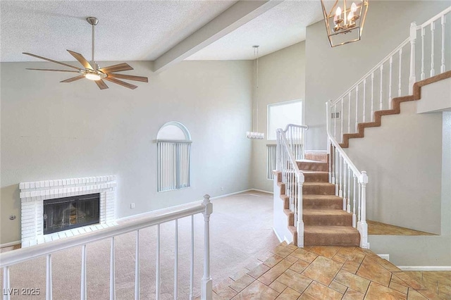 staircase featuring carpet floors, a fireplace, a textured ceiling, and baseboards