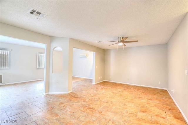 spare room with ceiling fan, a textured ceiling, visible vents, and baseboards