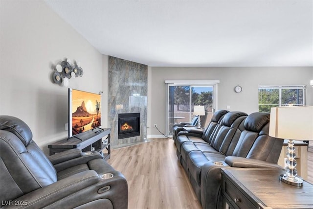 living room featuring a tiled fireplace, plenty of natural light, and light hardwood / wood-style flooring