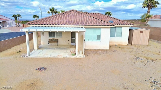 rear view of property with a patio and a storage unit