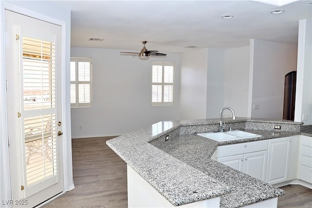 kitchen featuring light stone countertops, sink, light hardwood / wood-style flooring, and white cabinets