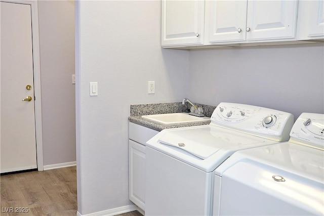 laundry area with cabinets, sink, independent washer and dryer, and light hardwood / wood-style floors