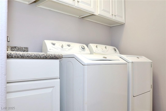 clothes washing area featuring cabinets and washer and dryer