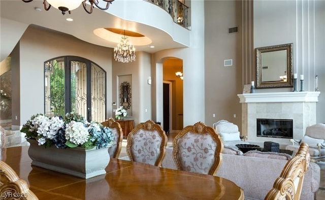 dining room with an inviting chandelier, a towering ceiling, and a tiled fireplace