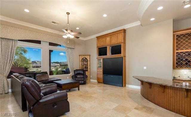 living room with ornamental molding, ceiling fan, and indoor bar