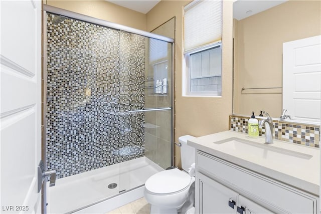 bathroom with vanity, backsplash, a shower with shower door, and toilet