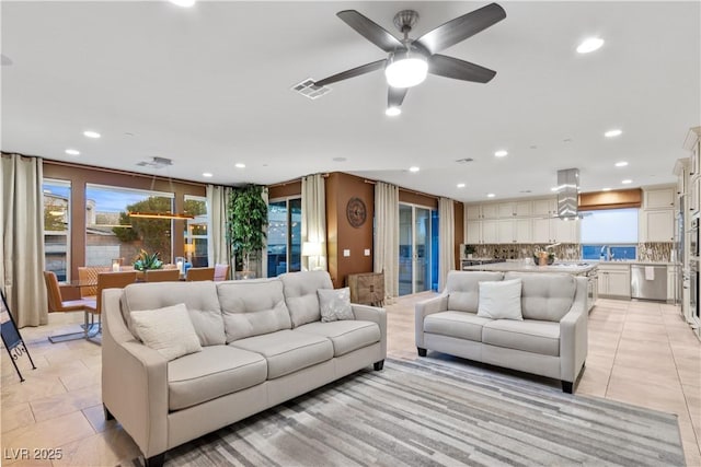 living room featuring light tile patterned floors, sink, and ceiling fan