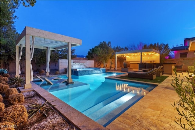 pool at dusk featuring an in ground hot tub, an outdoor hangout area, and a patio area